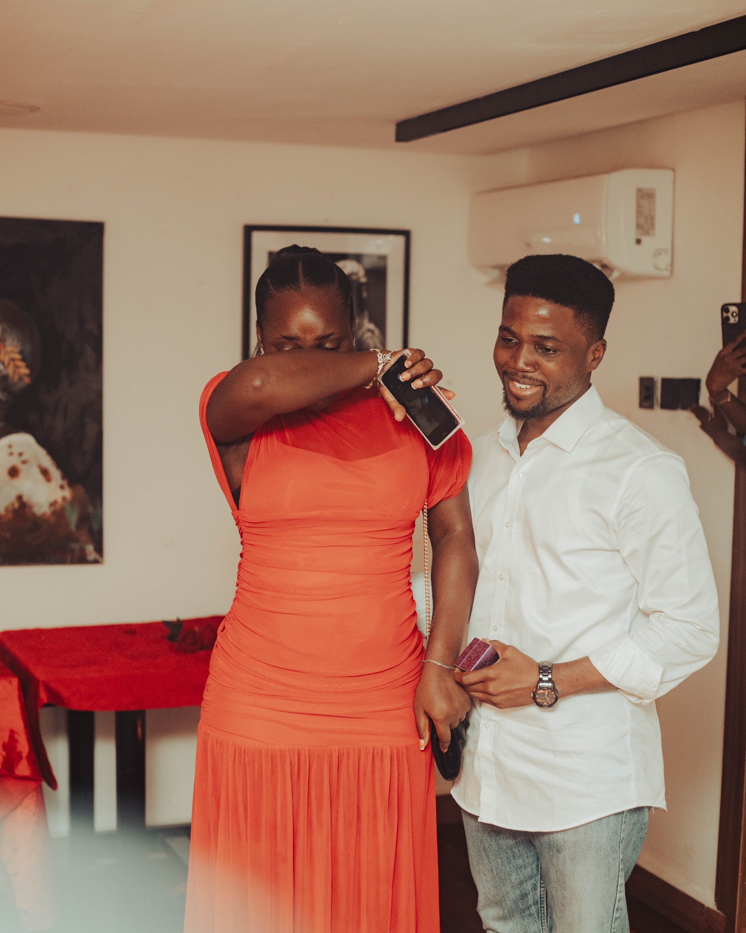 Fiye in a red dress, overcome with emotion as Kofo holds her hand